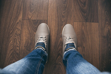 Grey shoes on wooden floor, legs in jeans