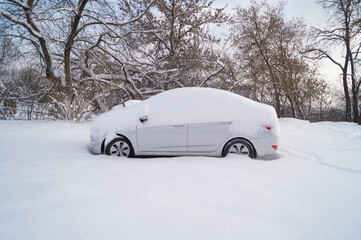 Winter, the car in the park is covered with snow.