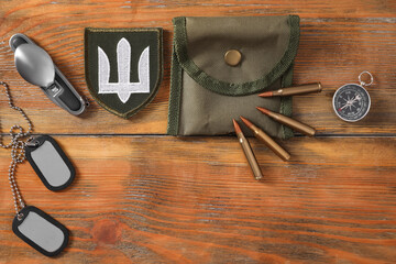 MYKOLAIV, UKRAINE - SEPTEMBER 26, 2020: Tactical gear and Ukrainian army patch on wooden table, flat lay. Space for text