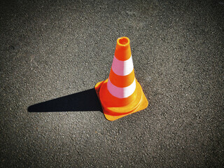 High angle shot of a single striped traffic road cone on a gr asphalt