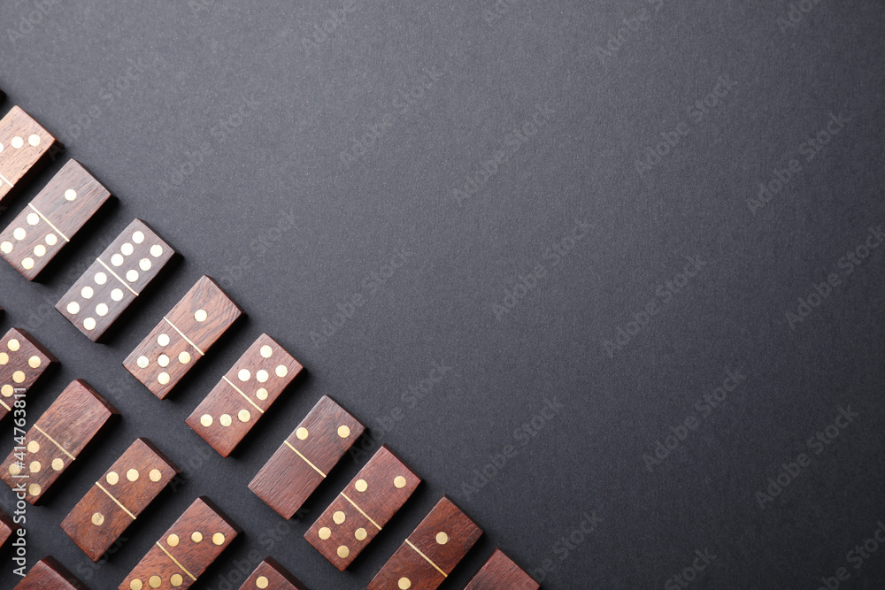 Sticker Wooden domino tiles on black background, flat lay. Space for text