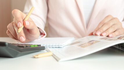 close up of woman hands with calculator counting and taking notes to notebook