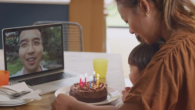 Asian mother with children at home celebrating birthday with father via video call and they sing happy birthday - shot in slow motion