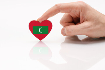 Love and respect Maldives. A man's hand holds a heart in the shape of the Maldives flag on a white...