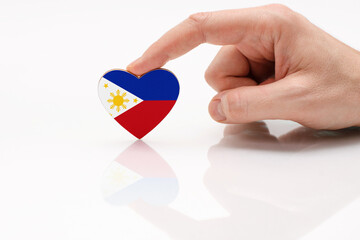 Love and respect Philippines. A man's hand holds a heart in the shape of the Philippines flag on a...