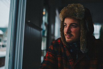 A man in winter gear gazing out a window 