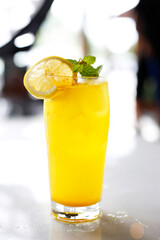 A glass of yellow drink, lemonade, cocktail in a bright interior.