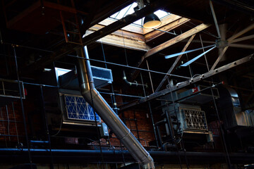 Naklejka premium Pipes, ceiling fans, vents, and windows in a dark warehouse