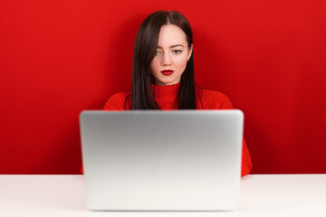 Naklejka premium beautiful girl at the computer on a red background