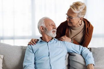 Happy mature couple sitting on sofa and communicating