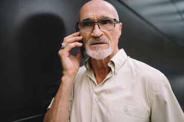 Close up of serious male senior in optical spectacles for provide eyes correction making international smartphone conversation in roaming, Caucasian man in classic glasses have consultancy call