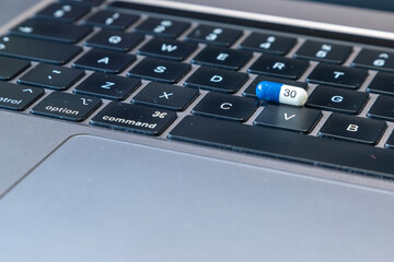Blue and white tablet pills on a black computer keyboard.