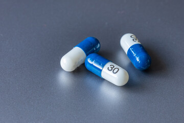 Blue and white tablet pills on a gray background.