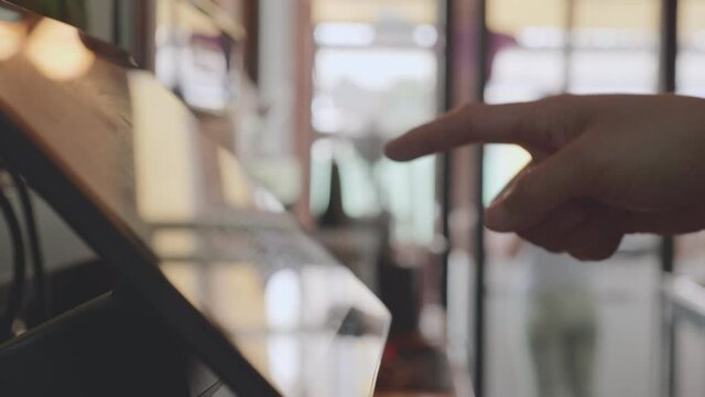 Close-up employee touches the screen of the automatic cash register and charges the customer at the counter.
