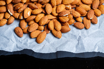 Delicious roasted sweet almonds lie in a large heap, nuts close-up.