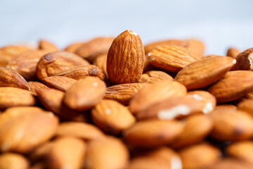 Delicious roasted sweet almonds lie in a large heap, nuts close-up.