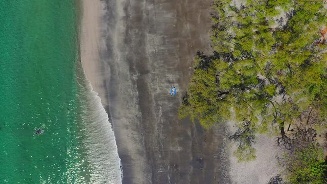 Aerial view from drone on caribbean sea beach with woman resting on sand. High quality 4k footage
