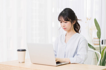 部屋でノートパソコンを使う若い女性