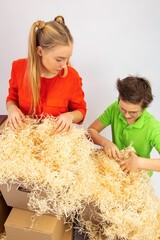 a girl and a boy near the cardboard boxes brought from the warehouse of the store are looking for their gift