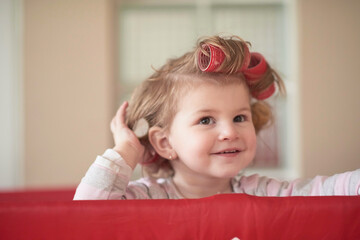 Fototapeta premium little baby girl with strange hairstyle and curlers