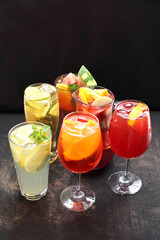 Set of various glasses with colorful lemonades, drinks, cocktails on a black stony background.