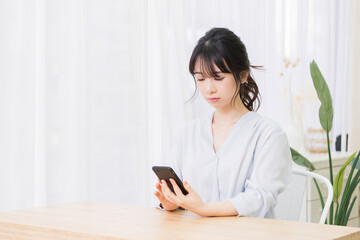 部屋でスマホを使う若い女性