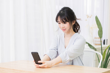 部屋でスマホを使う若い女性