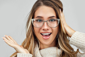 Girl in a sweater on a white wall background. Woman in glasses with a silver frame.