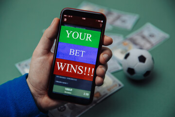 Man holds smartphone with bet application. Victory message. Gambling and bet concept.