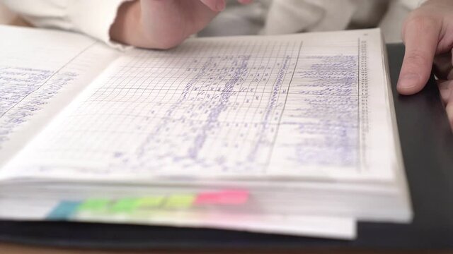 School journal or register with grades, close-up. The teacher checks the school journal