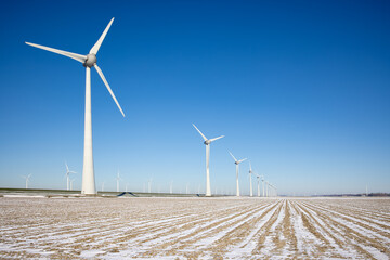 Dutch agricultural landscape with windturbines and fields covered with snow
