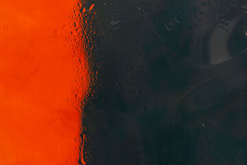 Bright red and dark blue, illuminated neon lights in street dew window glass with raindrops. Abstract blurred background