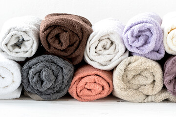 Obraz na płótnie Canvas Fragrant and fresh multi-colored terry towels in a roll on a wooden white background. 100% cotton