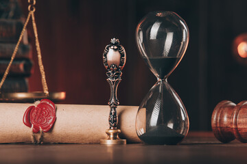 Wooden gavel, hourglass and antique stamp with last will on wooden table close-up.