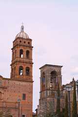Fototapeta premium Contraste entre torres de iglesia antigua y nueva con cielo nublado