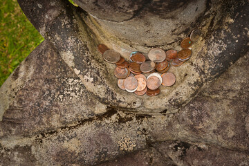 Coins left by visitors in hands of a statue of Buddha, Byodo-In Buddhist Temple Oahu, Hawaii, USA