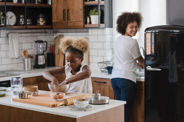 Mother Teaching Child to Cook and Help in the Kitchen. African American Mother and Daughter making cookies at home. 