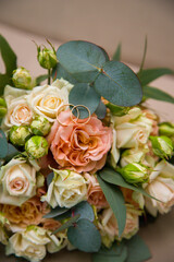 wedding gold rings lie on the wedding bouquet of roses.
