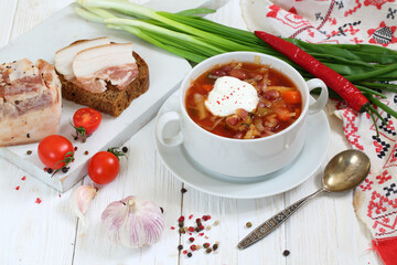 Borsch with bacon, black bread on a white wooden background