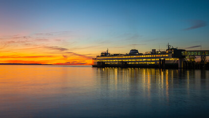 Ferry Boat on the sunset run prepares to sail towards the orange and gold colors of the setting sun