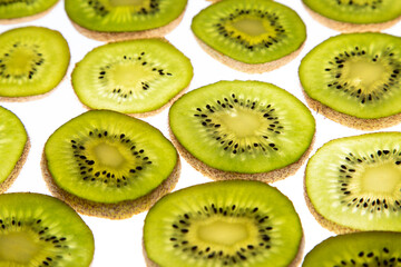 Ripe and green kiwi sliced with seeds visible on white background