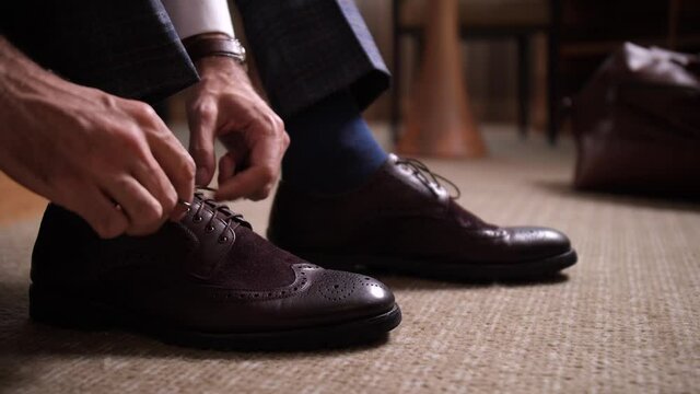 Close-up of male hands tying shoes, businessman going to meeting with business partners from hotel room. Dressing for business meeting, respectable appearance, formal clothing, dress code