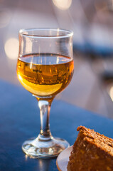 A glass of white dessert wine and a carrot pie on the table in a cafe