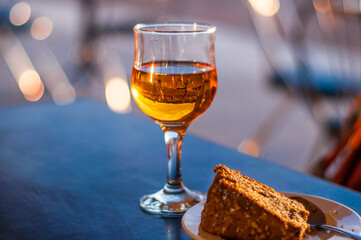 A glass of white dessert wine and a carrot pie on the table in a cafe