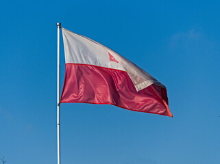 Polish flag against the blue sky. Polish flag in the wind. Waving Polish flag