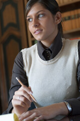 Giovane donna riflessiva con la matita in mano in uno studio legale