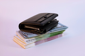 A large bundle of dollars and euros with a wallet on a light background.