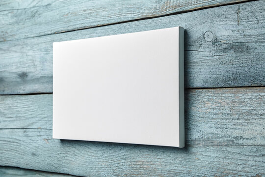 Canvas hanging on light blue wooden wall, white canvas print mockup