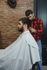 Serious Young Bearded Man Getting Haircut By Barber. Barbershop Theme