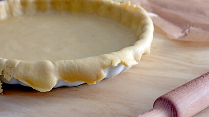 The process of making a base for a shortcrust quiche pie, male hands transfer a rolled dough sheet into a baking dish. Authentic home hobby home baker. Pie crust recipe